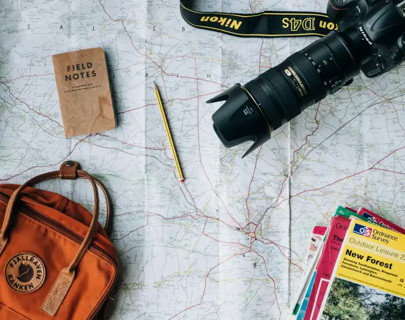 Landkarte mit Notizbuch, Kamera und Rucksack für die Reiseplanung